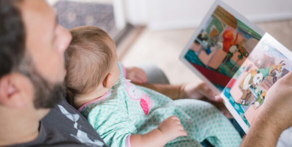 person carrying baby while reading book